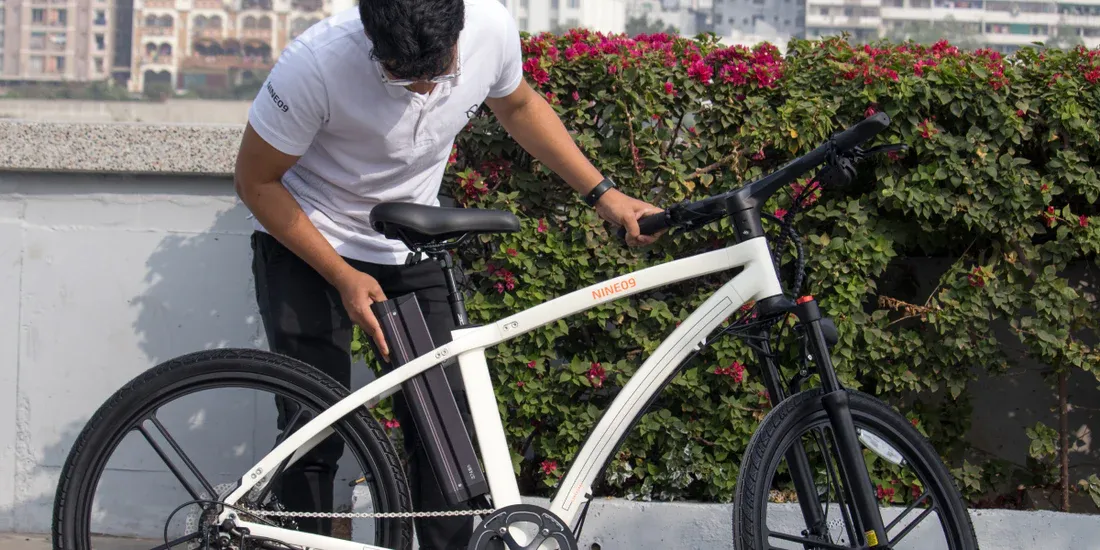 Rowerzysta wkłada wyjmowaną baterię do białego roweru elektrycznego NINE09 przed długą trasą
