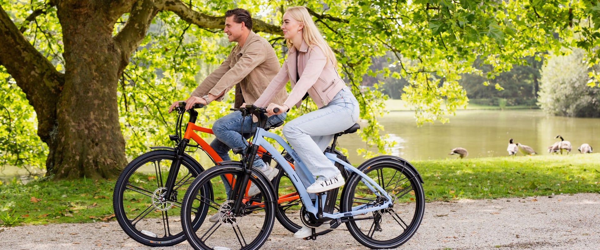 Two riders on NINE09 electric bikes in a park, riding within Europe's 25 km/h eBike speed limit